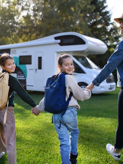 rear-view-of-young-family-with-backpacks-going-to-rv